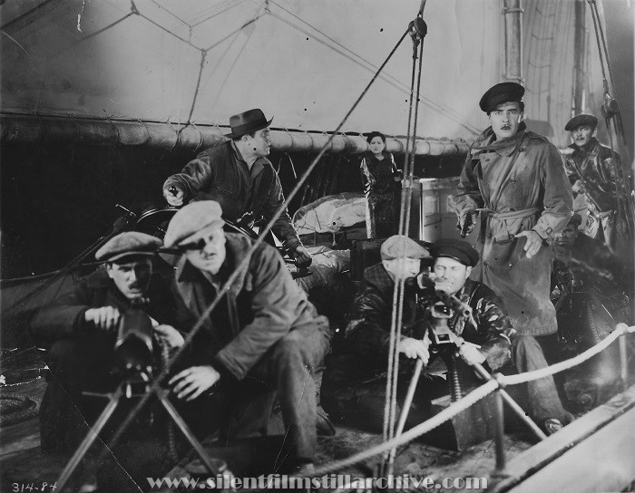 Bootleggers man machine guns as Joan Crawford and John Gilbert watch in TWELVE MILES OUT (1927)